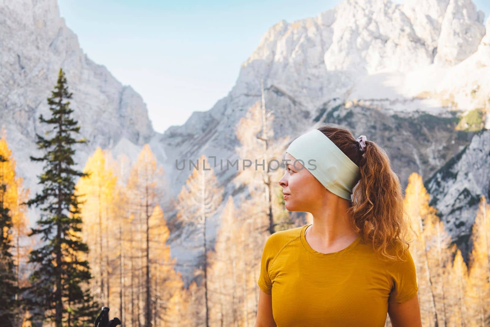 Waist up woman, fall autumn hiker girl outdoor in the forest fixing up her headband.. Happy caucasian woman hiking outdoors. High quality photo