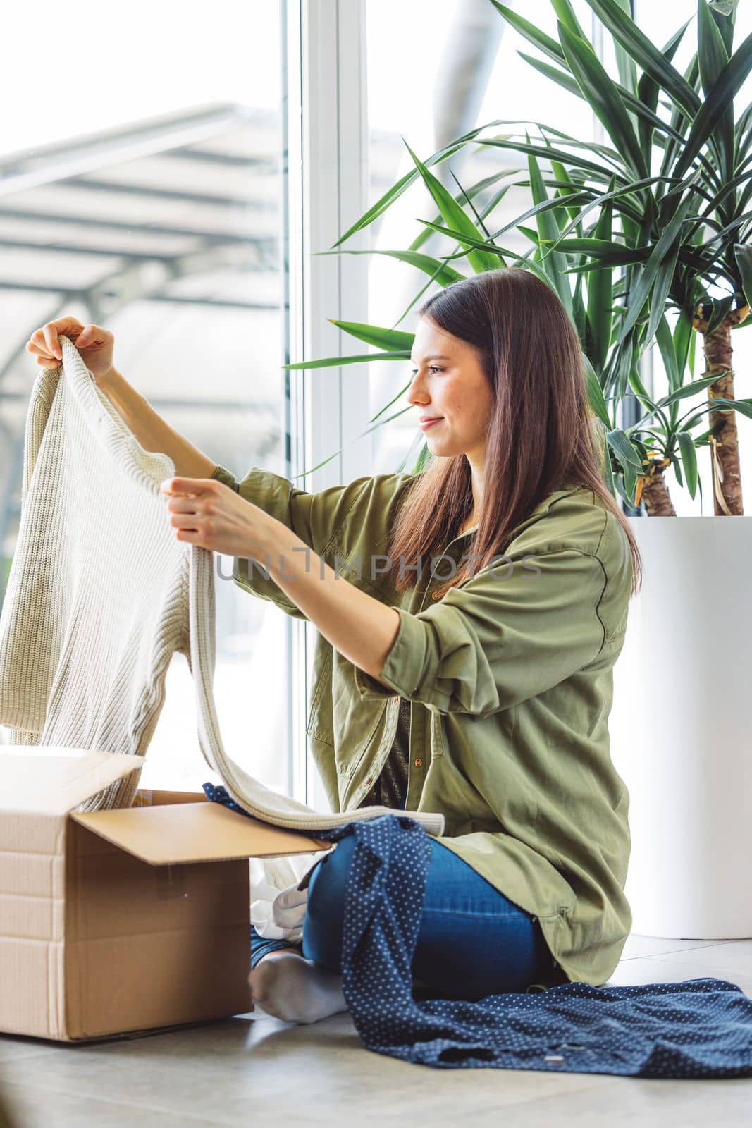 Young caucasian woman receiving a big box of her online orders. Woman opening the package, getting excited to see the stuff she bought. High quality photo