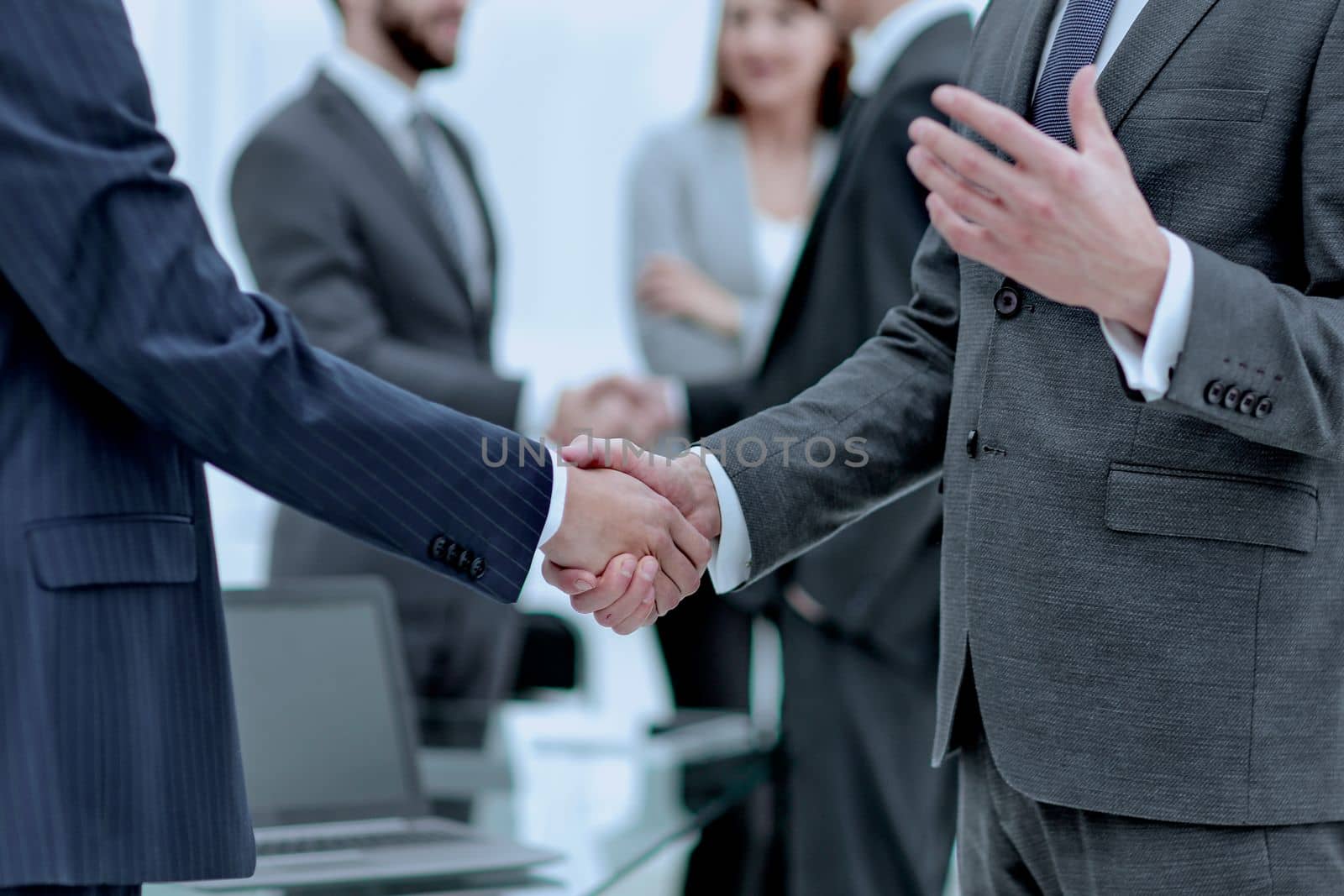 Business partners handshaking over business objects on workplace by asdf