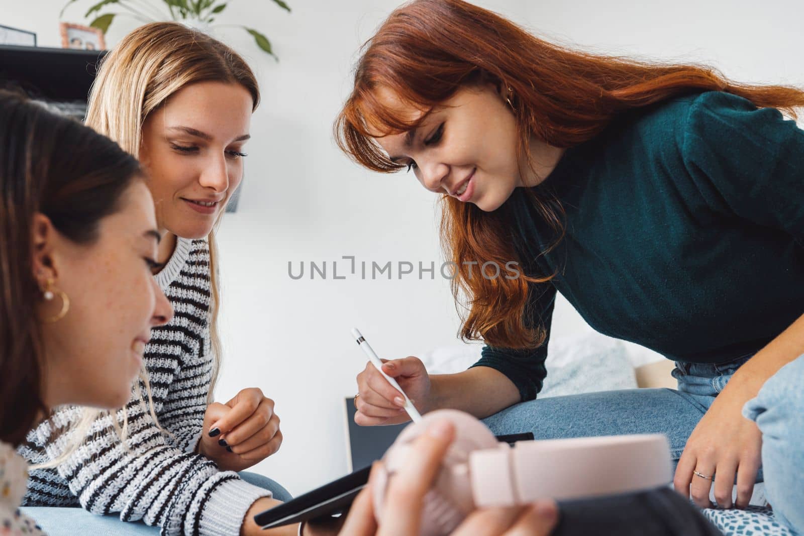 Group of three roommates, college student, young caucasian women, spending time together in their room, studying, talking, having fun, laughing.