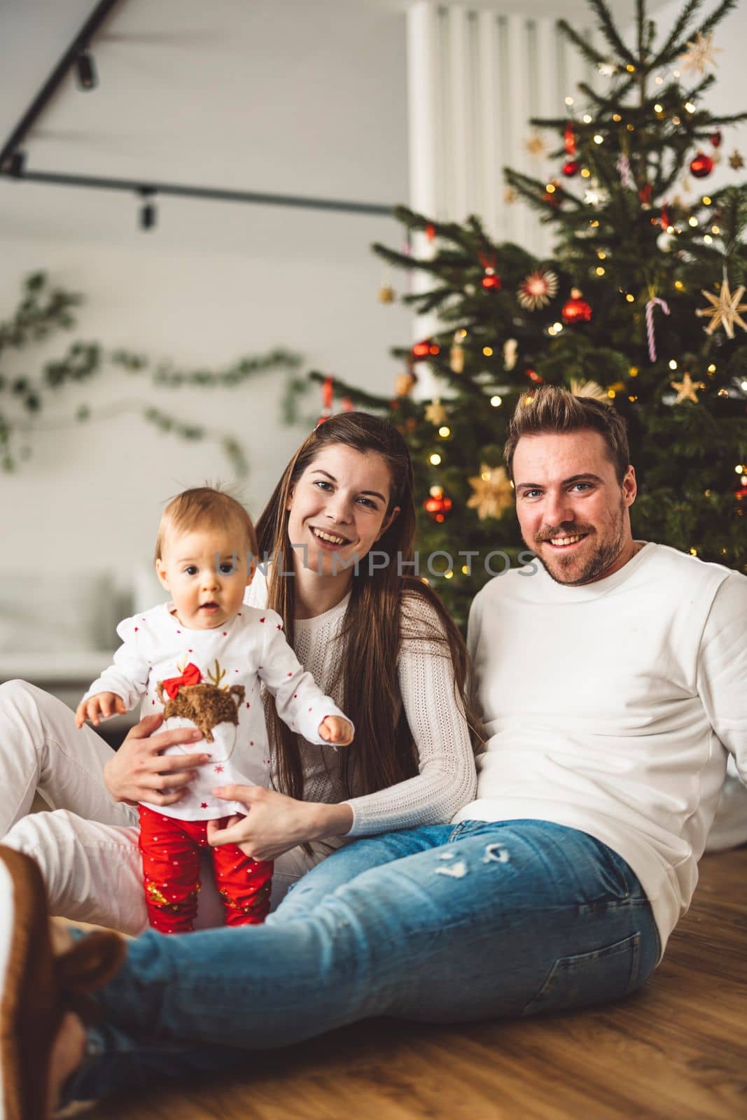 Smiling family of three Christmas portrait - Family sitting in front of the Christmas tree by VisualProductions