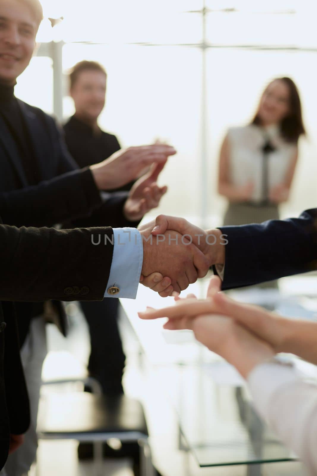 close up. business partners shaking hands with the applause of the business team .