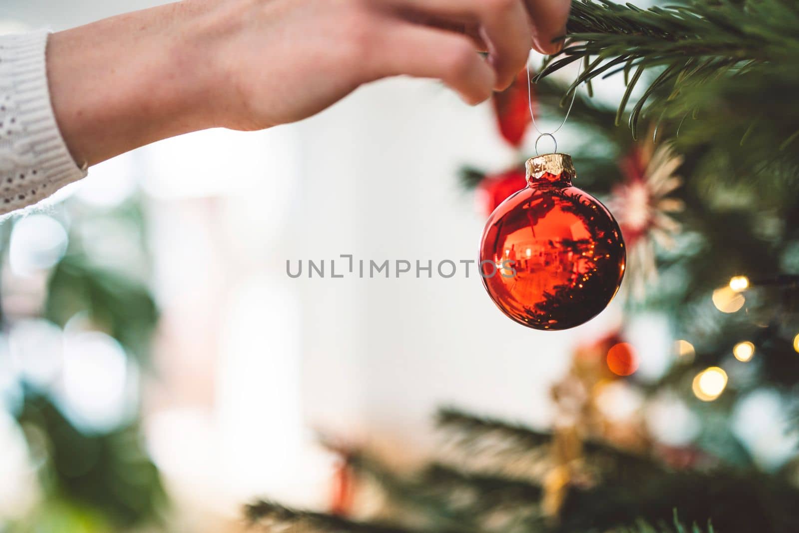 Close up on a red Christmas ornament being put on the Christmas tree by VisualProductions