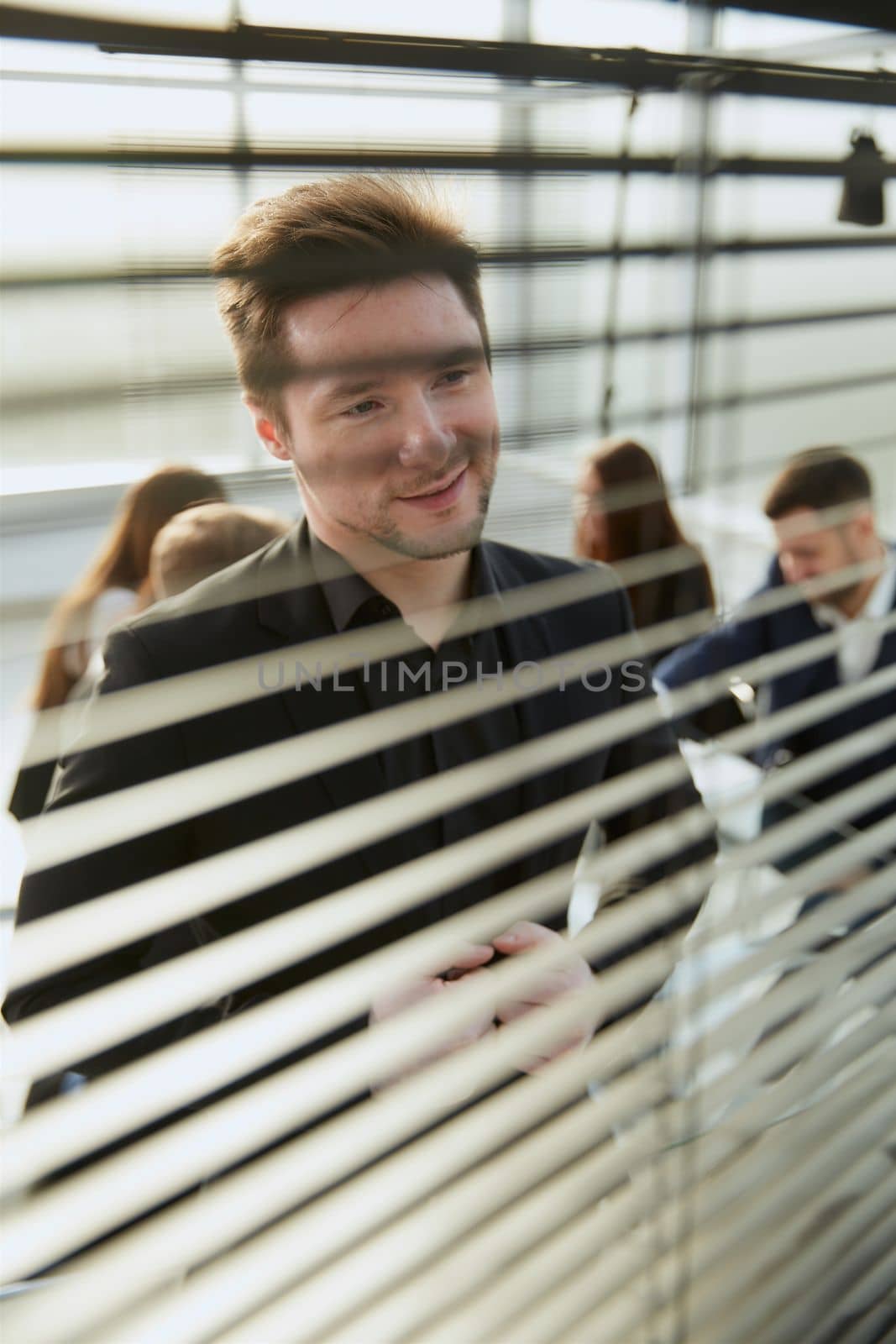 close up. smiling employee looking through office blinds . business concept.