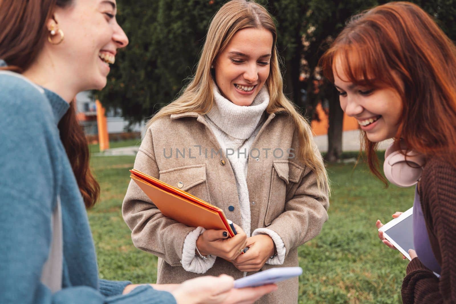 Young caucasian women, friends laughing, close up photo, smiling while on a break outside by VisualProductions