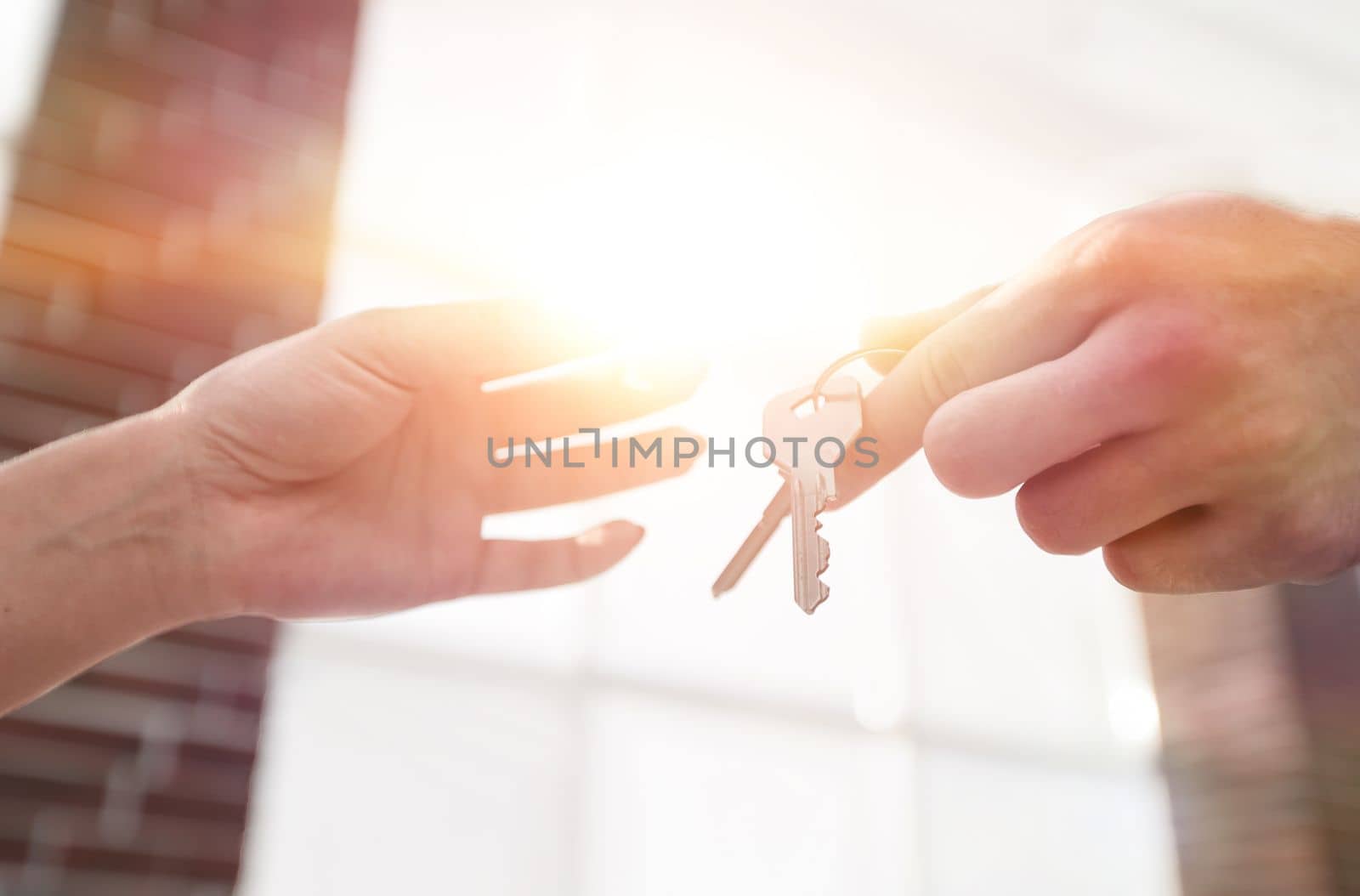 Female hand giving keys from new apartment to male hand on blurred background