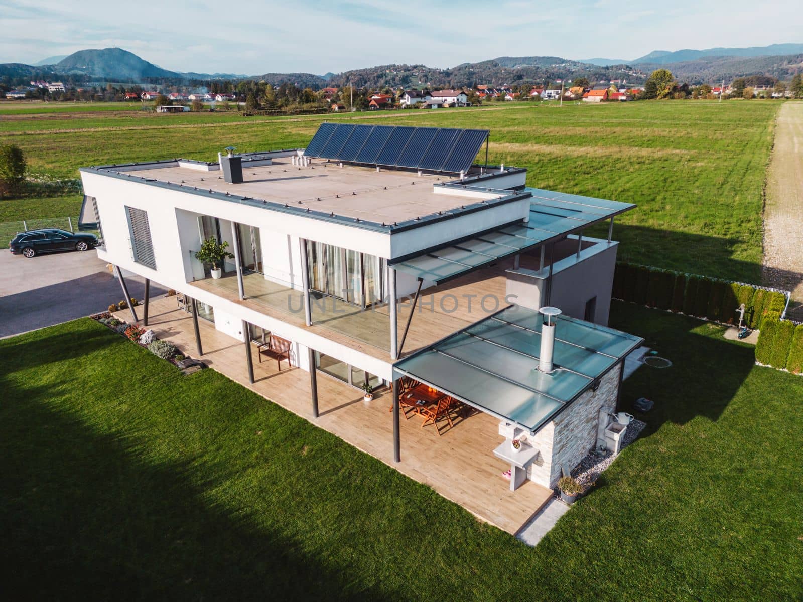 Aerial view of a modern house with solar panels on the roof top. Modern architecture, suburban home, country side living, luxury lifestyle. Renewable energy, solar panels. 