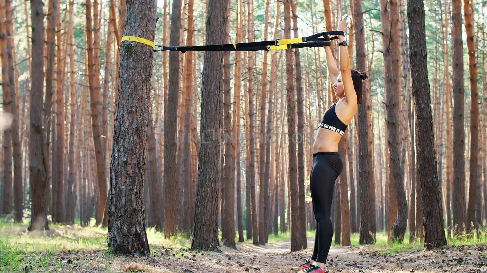 Beautiful, athletic, sexy young woman, coach, instructor, performs exercises, doing exercises. In pine forest, in summer, in sun rays. by djtreneryay