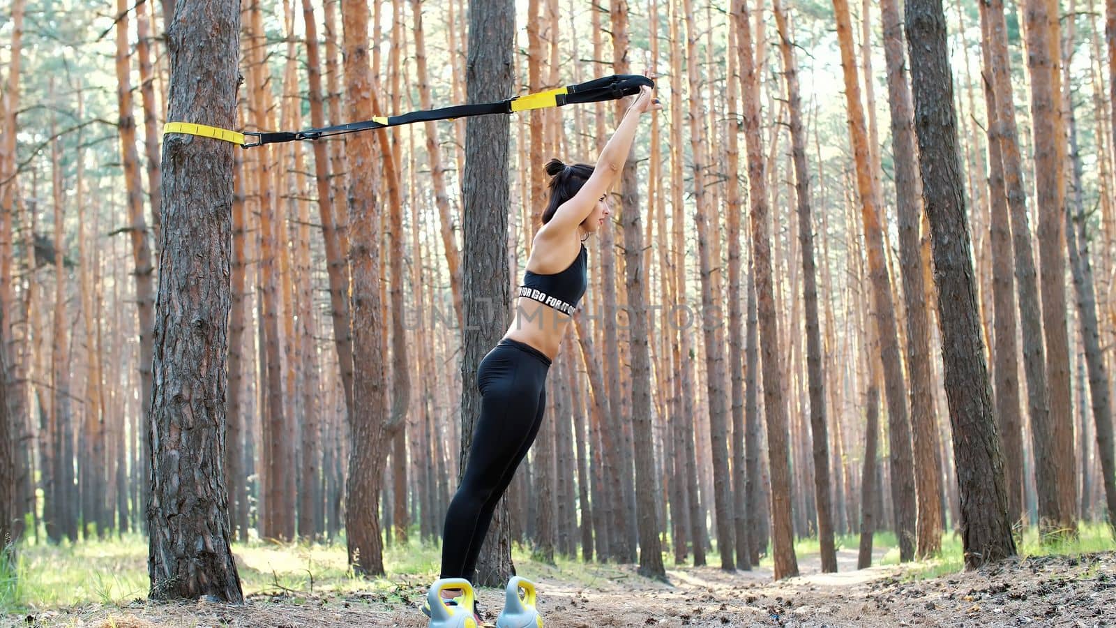 Beautiful, athletic, sexy young woman, coach, instructor, performs exercises, doing exercises. In pine forest, in summer, in sun rays. by djtreneryay