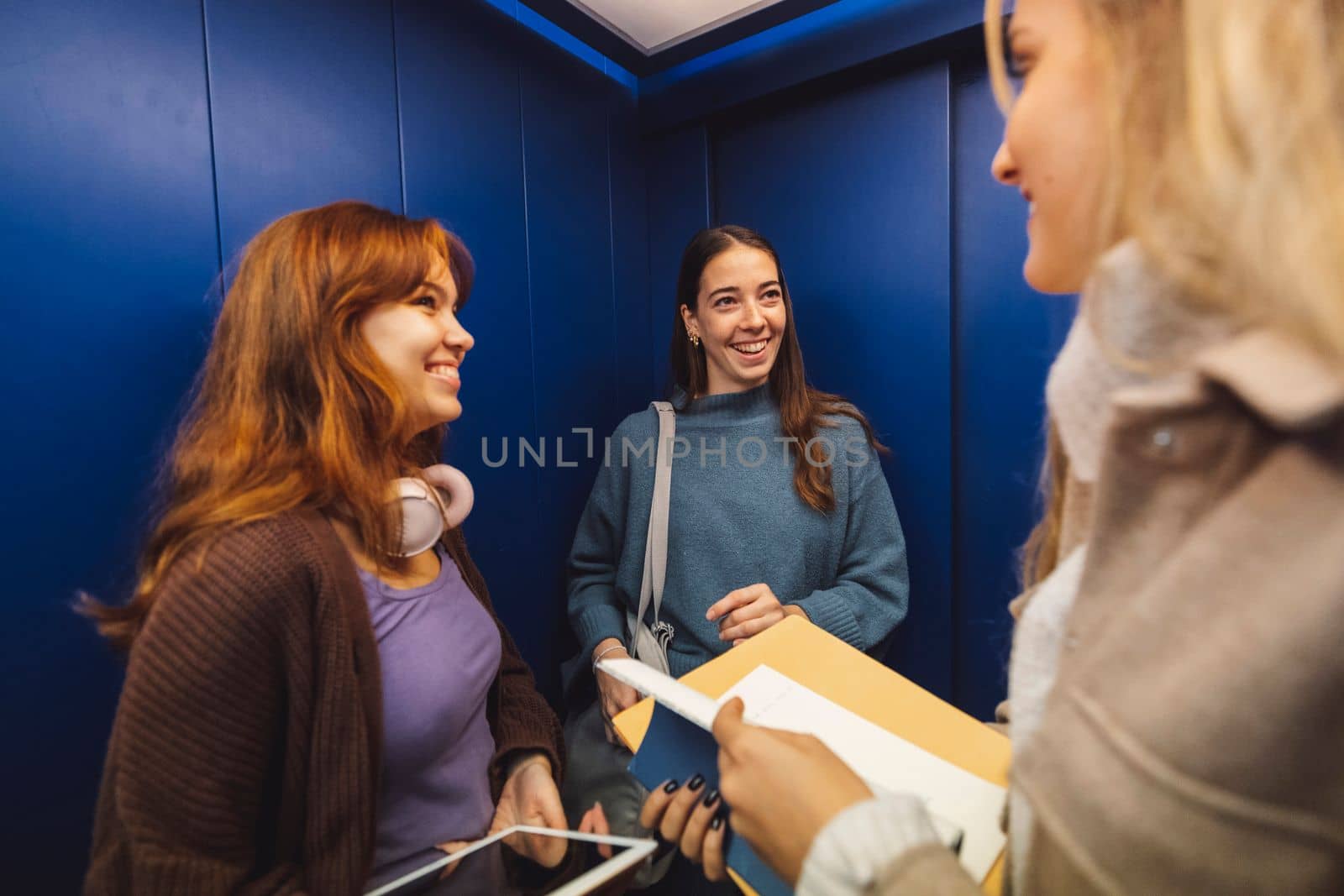 Three cheerful young women in the elevator on their way to class by VisualProductions