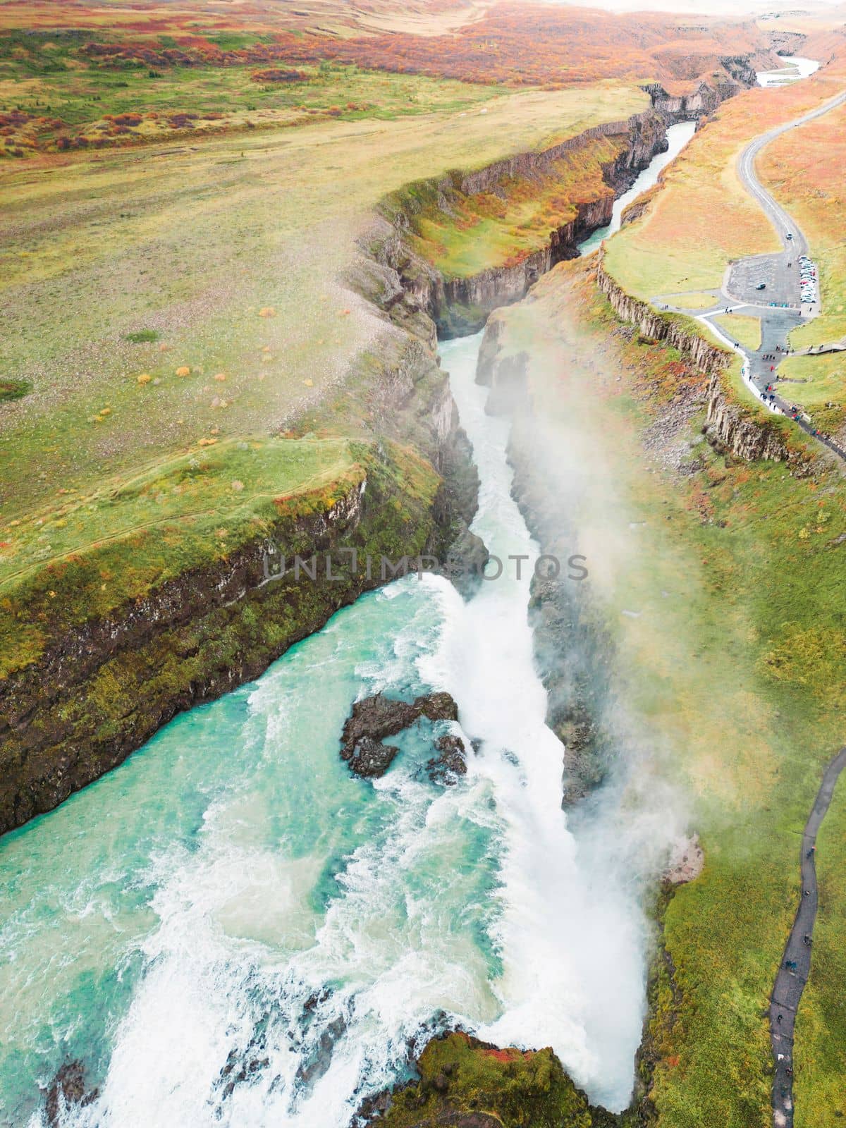 Huge beautiful waterfall Gullfoss, famous landmark in Iceland. River foaming whilst falling down the waterfall, tourist waling by, looking at the waterfall from a view point. High quality photo