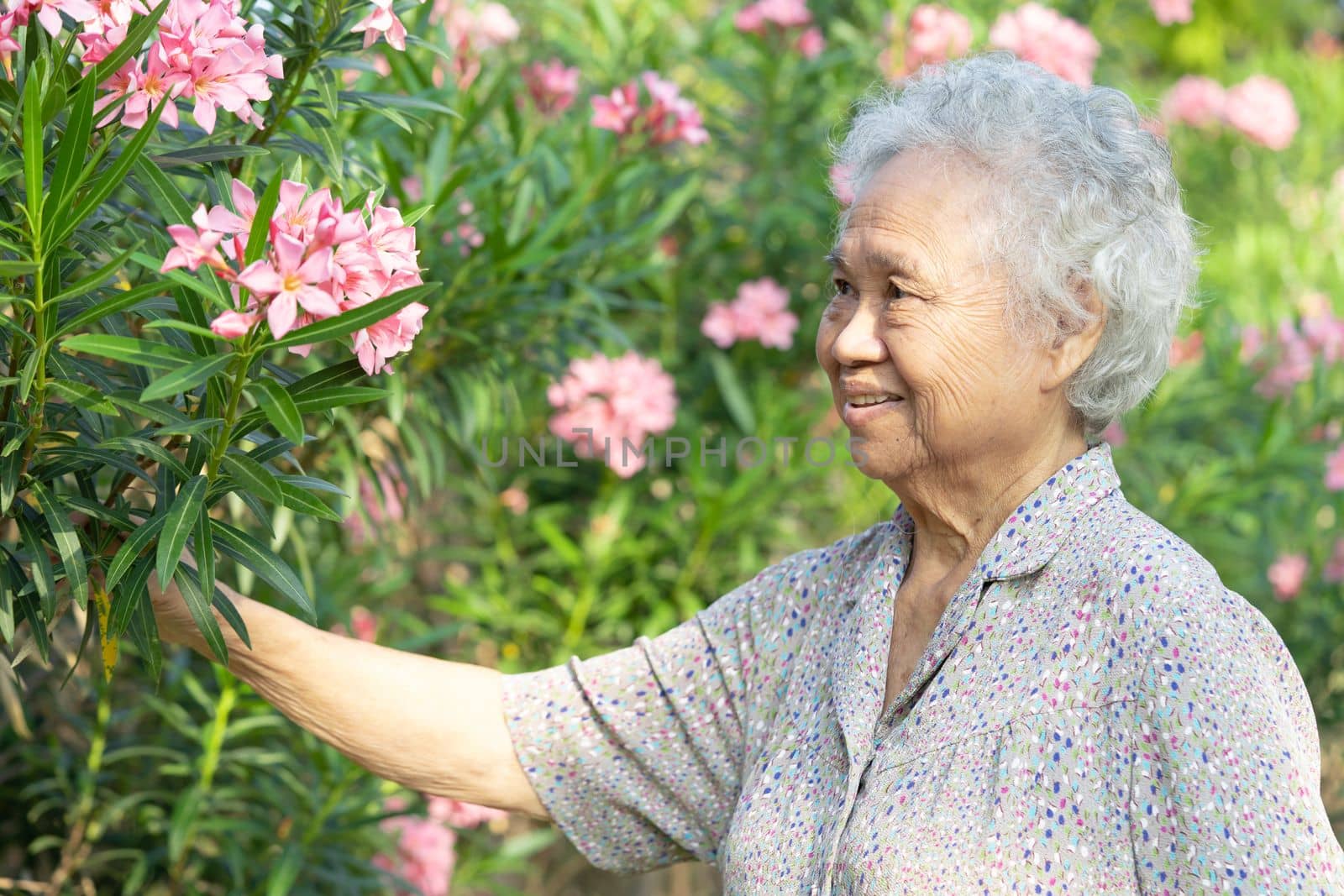 Asian senior or elderly old lady woman walk for exercise with flower in park. by pamai