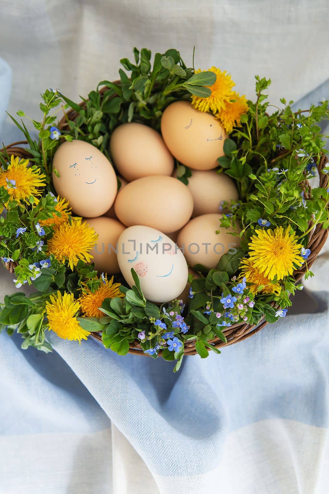 A beautiful spring bouquet in a wooden basket with Easter painted eggs, eggs with a cute face
