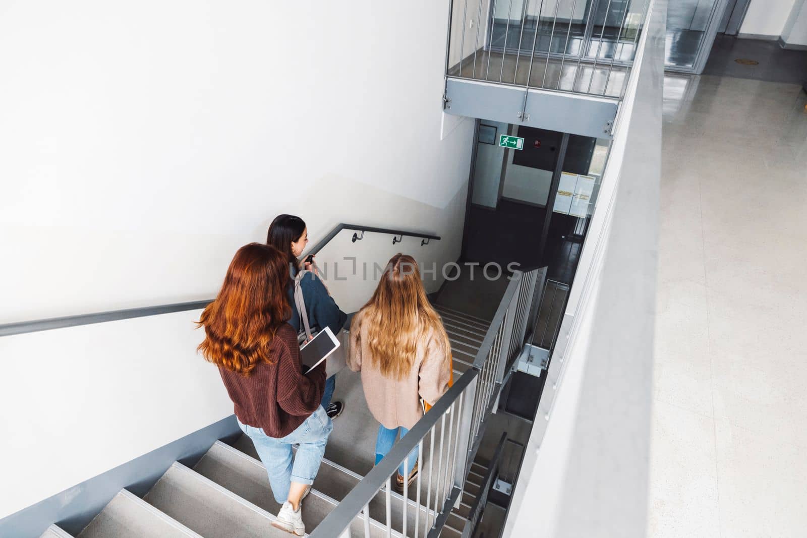 View from the top of the staircase of three students walking down the stairs  by VisualProductions