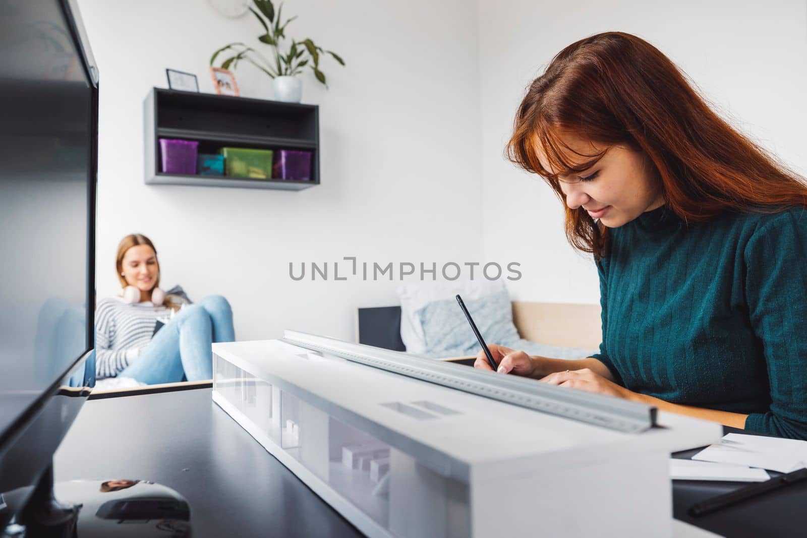 Two young caucasian women, college students studying together in their dorm room in a bright modern room. 
