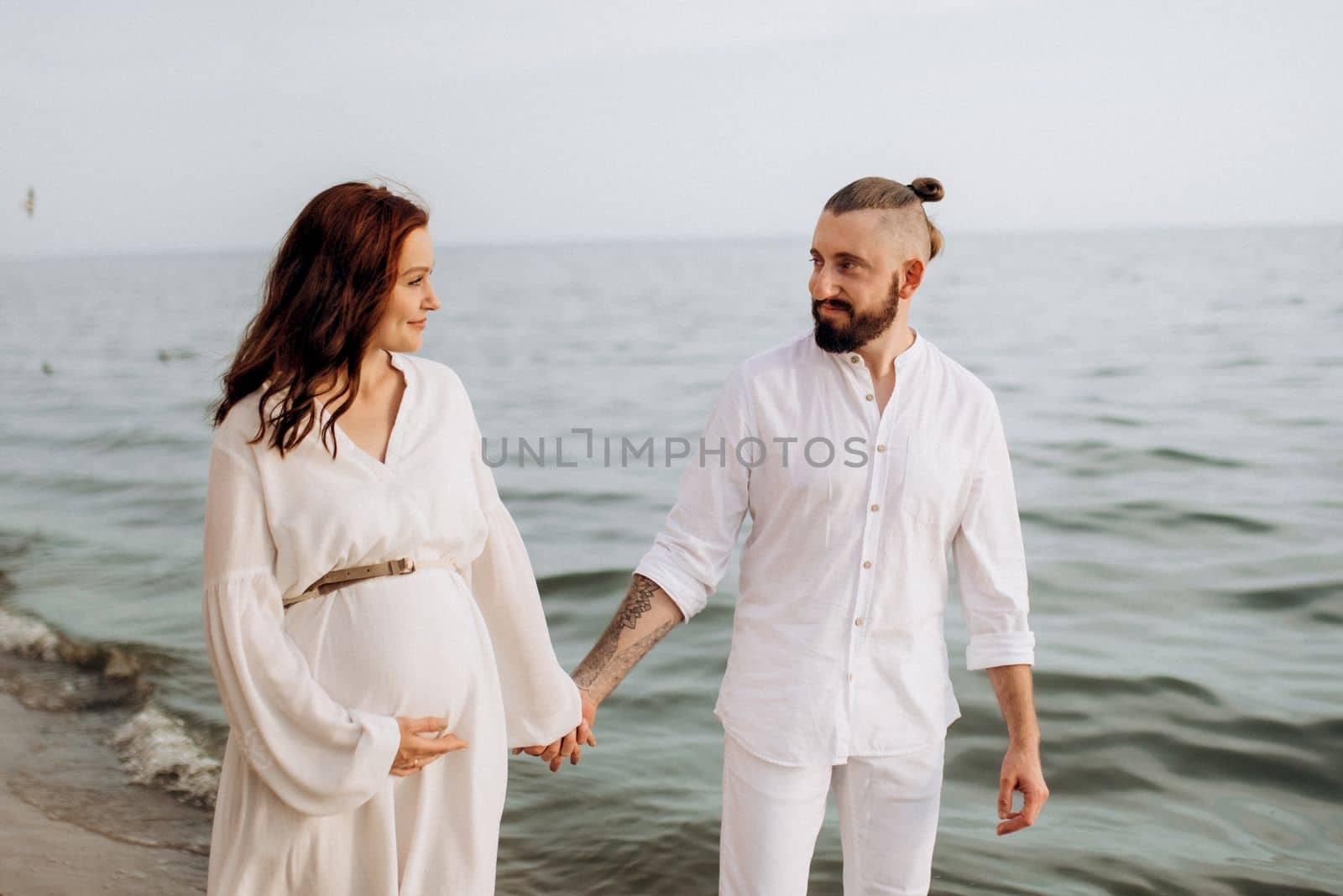 a guy with a girl in white clothes on the seashore next to clay cliffs