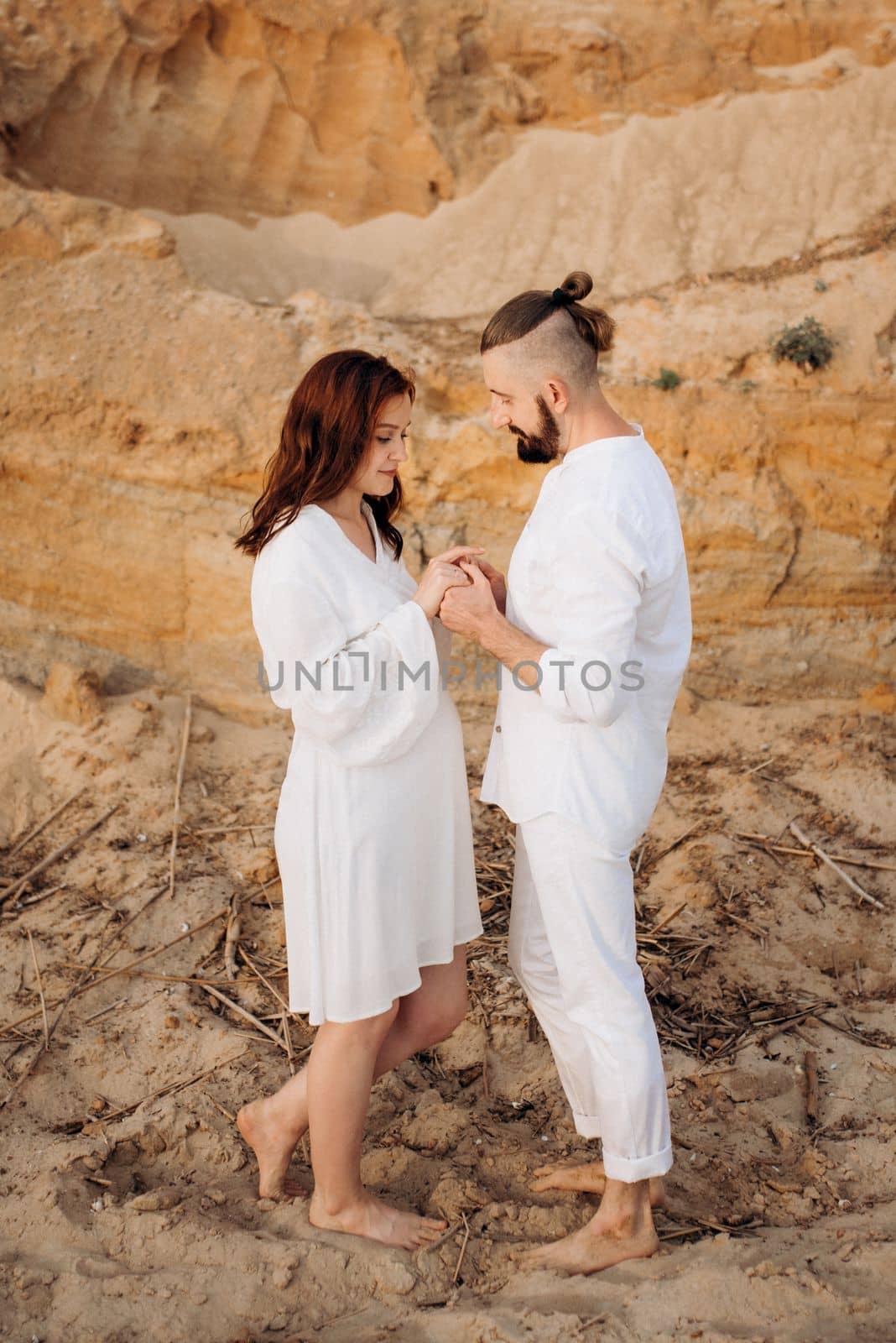 a guy with a girl in white clothes on the seashore next to clay cliffs