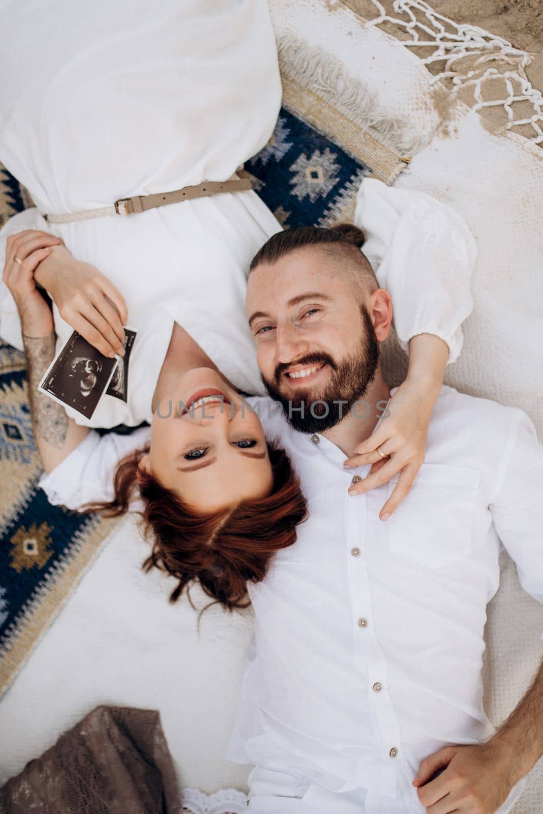 pregnant girl and boyfriend on a picnic by the sea in white clothes