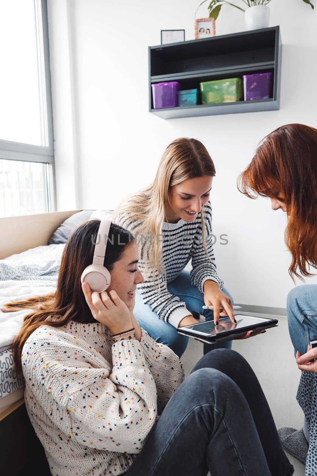 Group of three roommates, college student, young caucasian women, spending time together in their room, studying, talking, having fun, laughing. 