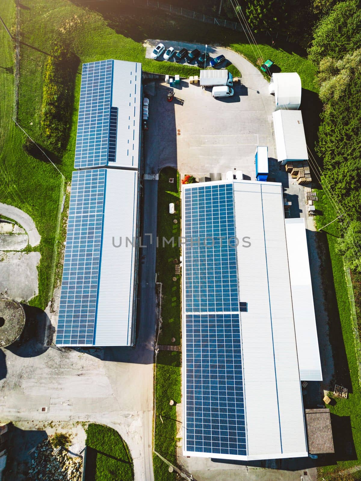 Vertical photo top down aerial view solar panels on the roof of two warehouses in the countryside by VisualProductions