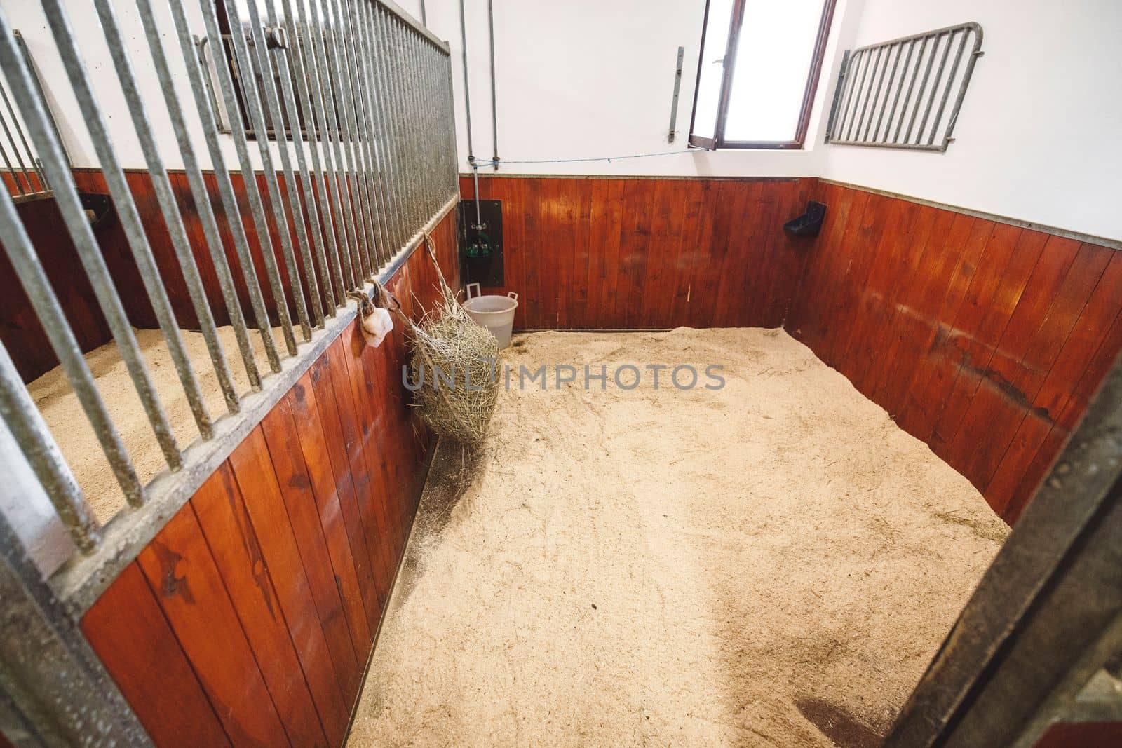 Empty stable, no horses inside the stables. Clean and empty horse boxes with fresh hay at the ranch. 