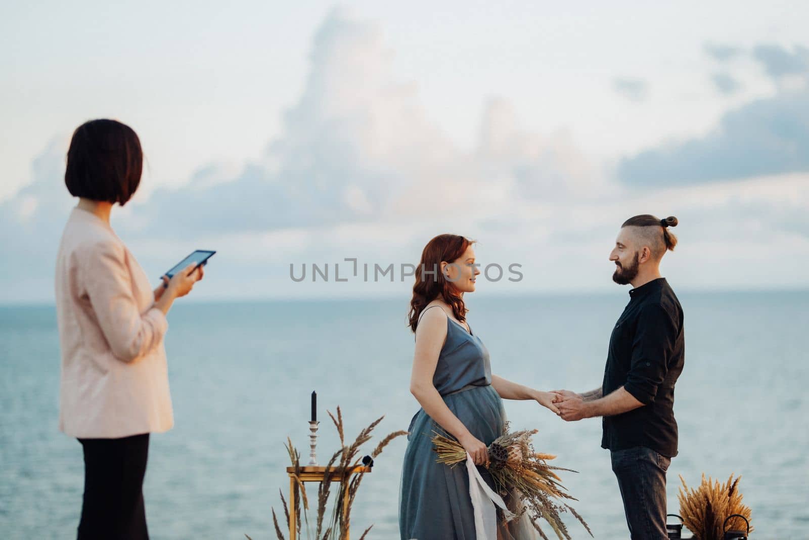 wedding ceremony of a girl and a guy on high hills near the sea