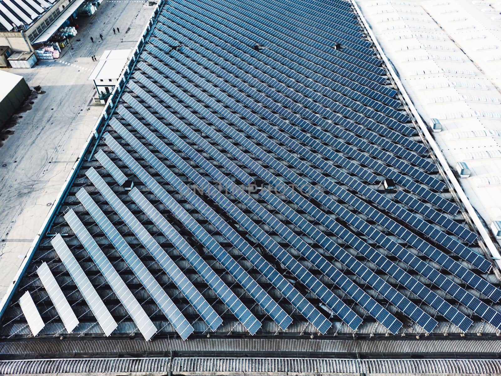 Aerial view of solar panels on industrial buildings. Drone point of view, flying over industrial area, with roof tops covered in solar panels.