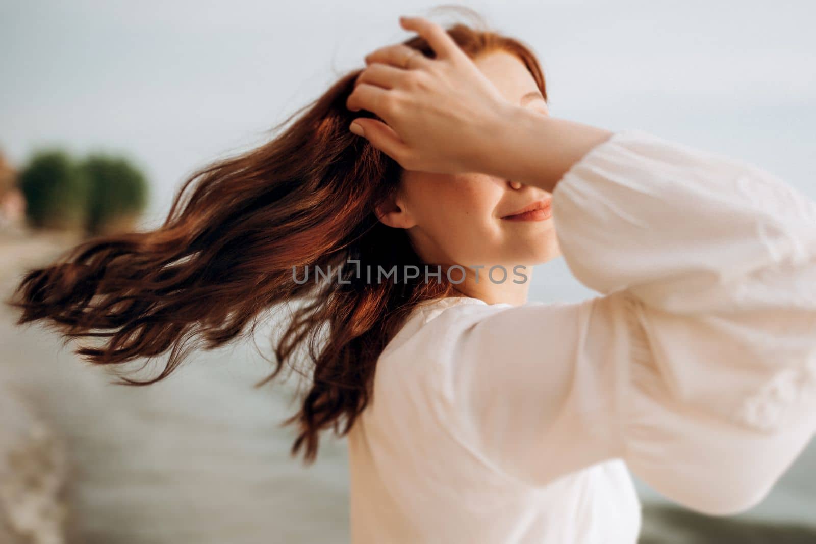 pregnant girl with brown hair on the seashore in white clothes