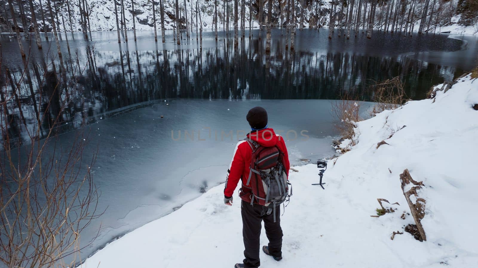 A guy standing on the shore admires mountain lake by Passcal