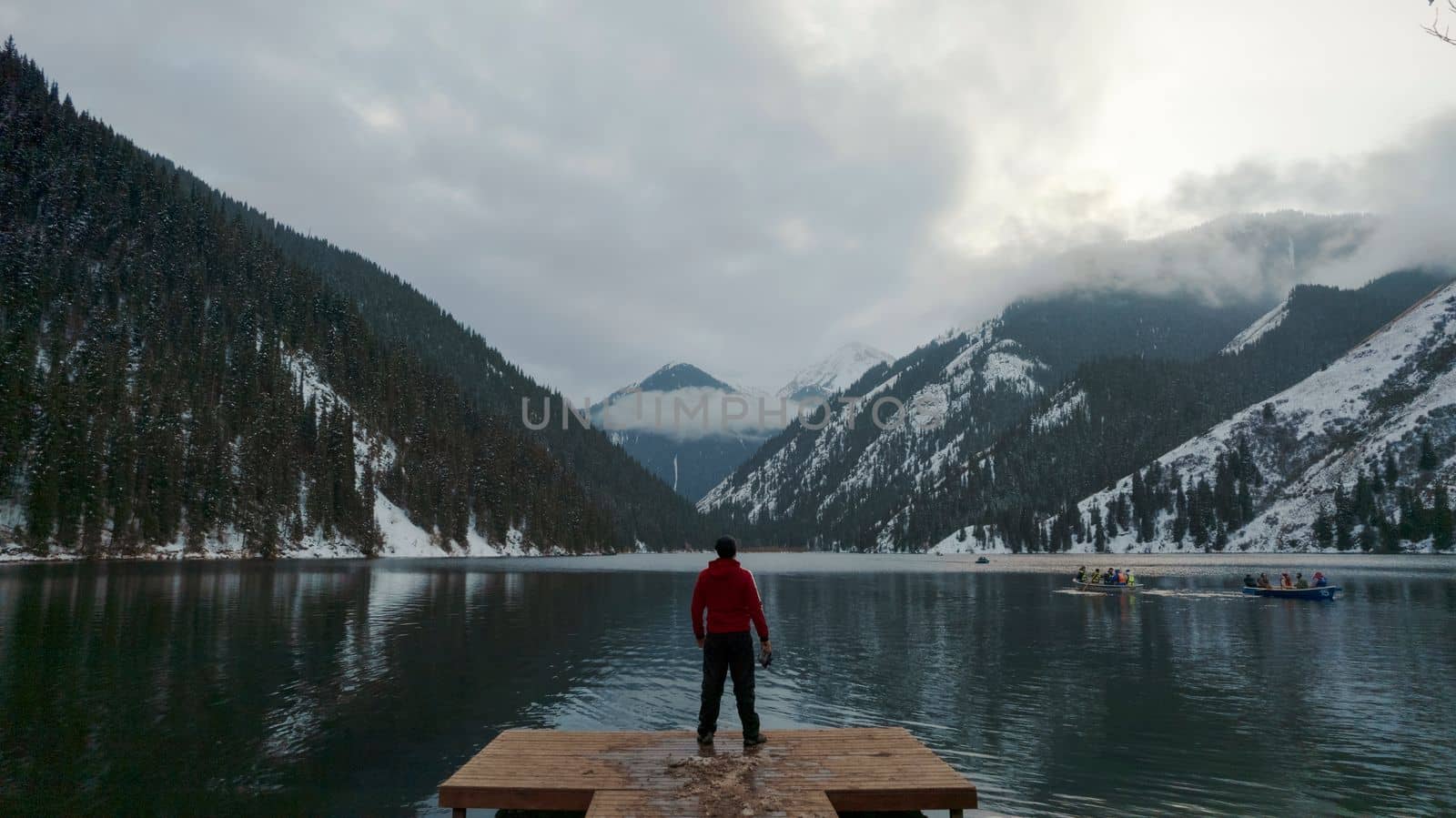 The guy standing on the pier admires mountain lake by Passcal