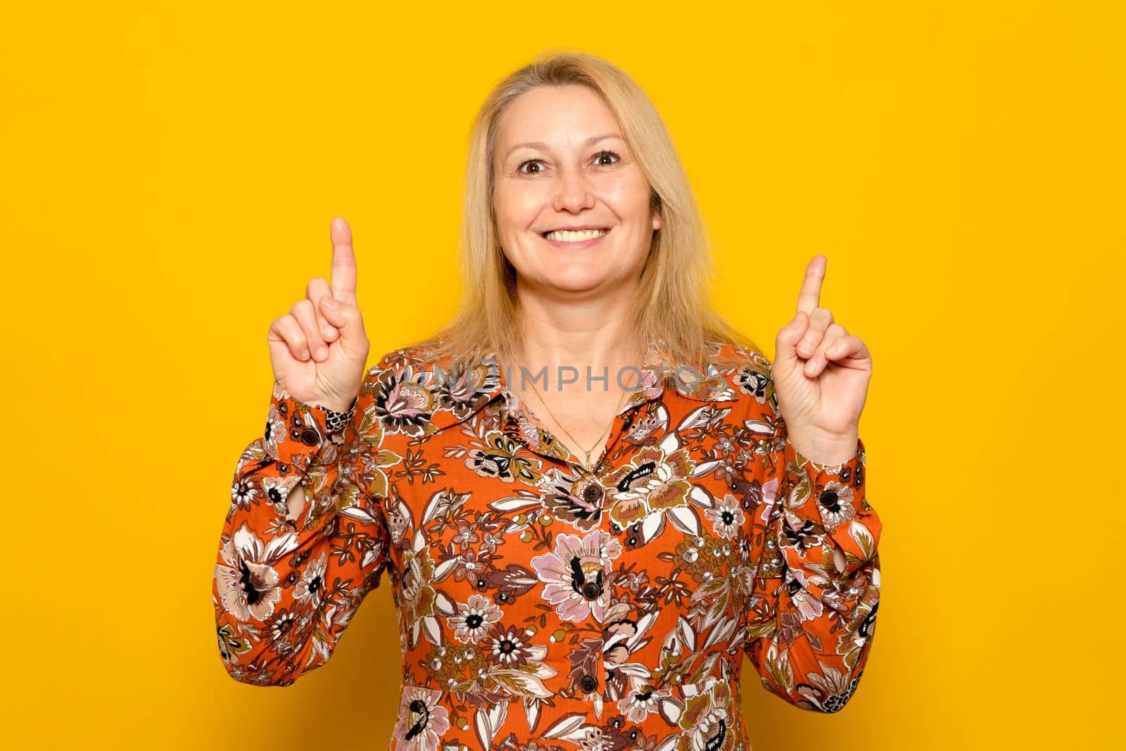 Image of smiling confident businesswoman, caucasian female pointing finger up, showing banner or sale information, standing over yellow background. by Barriolo82