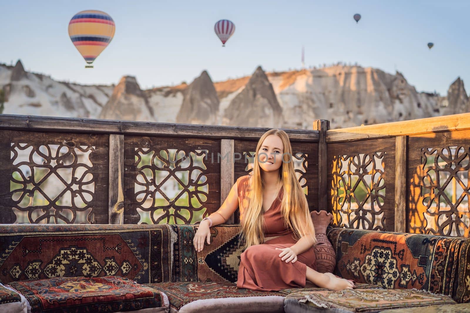 Tourist woman looking at hot air balloons in Cappadocia, Turkey. Happy Travel in Turkey concept. Woman on a mountain top enjoying wonderful view.