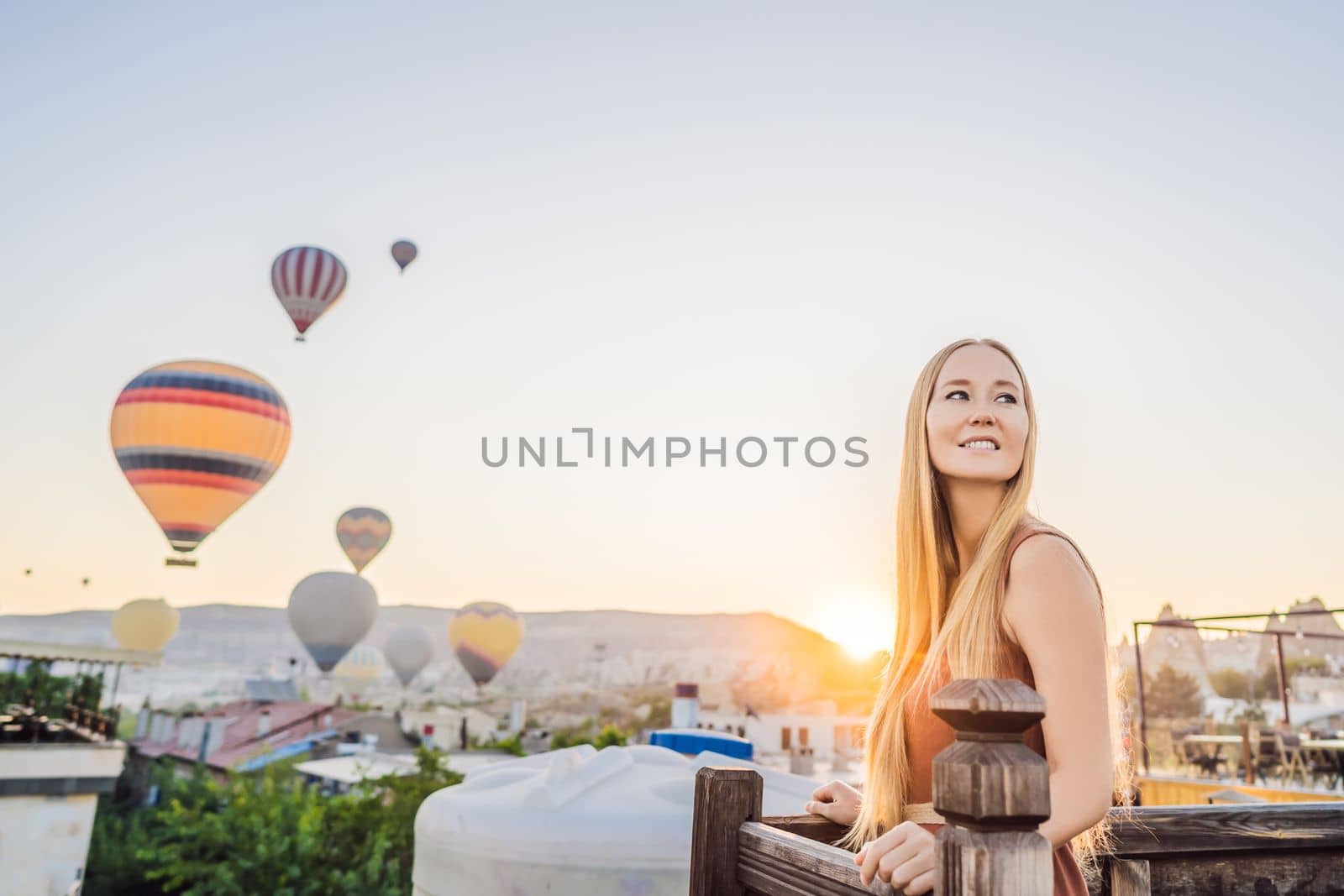 Tourist woman looking at hot air balloons in Cappadocia, Turkey. Happy Travel in Turkey concept. Woman on a mountain top enjoying wonderful view.