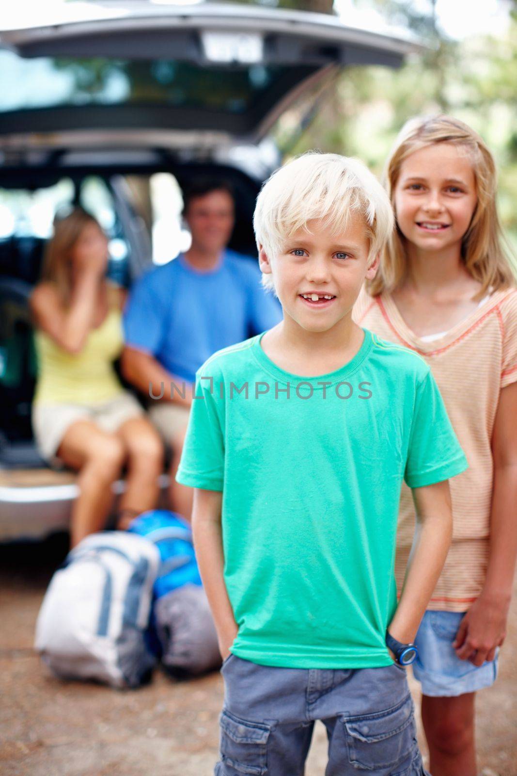 Cute young boy smiling. Portrait of young brother and sister smiling with parents sitting in the car