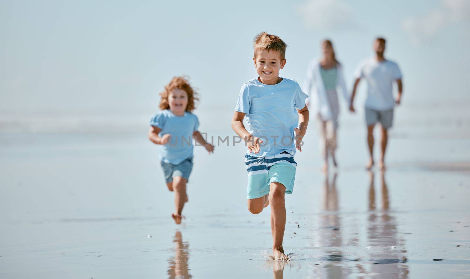 Children, running and beach with a brother and sister together on the sand by the sea or ocean during summer. Family, travel and fun with sibling kids on the coast with their parents for holiday.