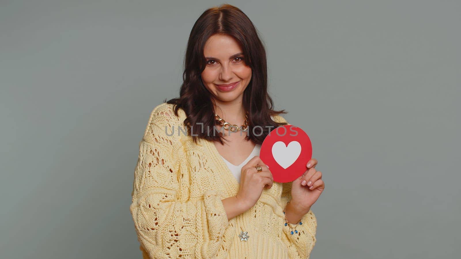 Like. Hipster one pretty woman show heart banner inscription agrees with something, gives positive reply recommends advertisement likes good. Young girl isolated alone on gray studio background