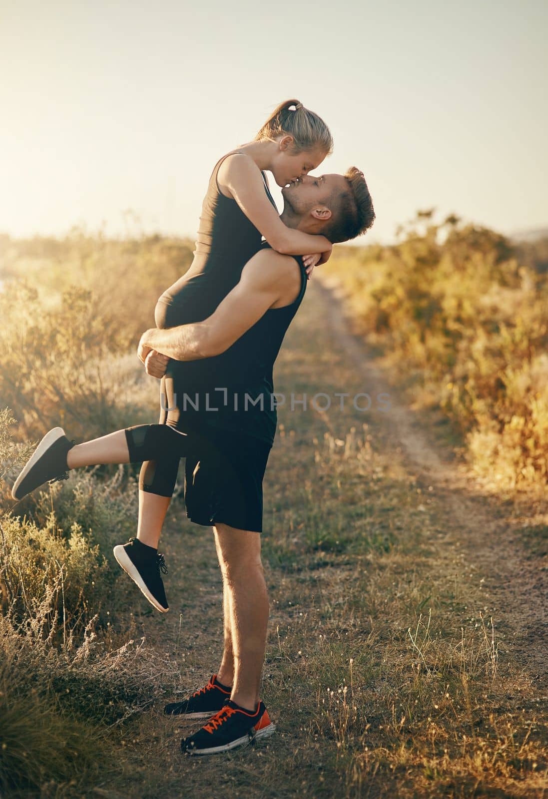 Elevated kisses are the best. a young man kissing his girlfriend while he is lifting her outdoors