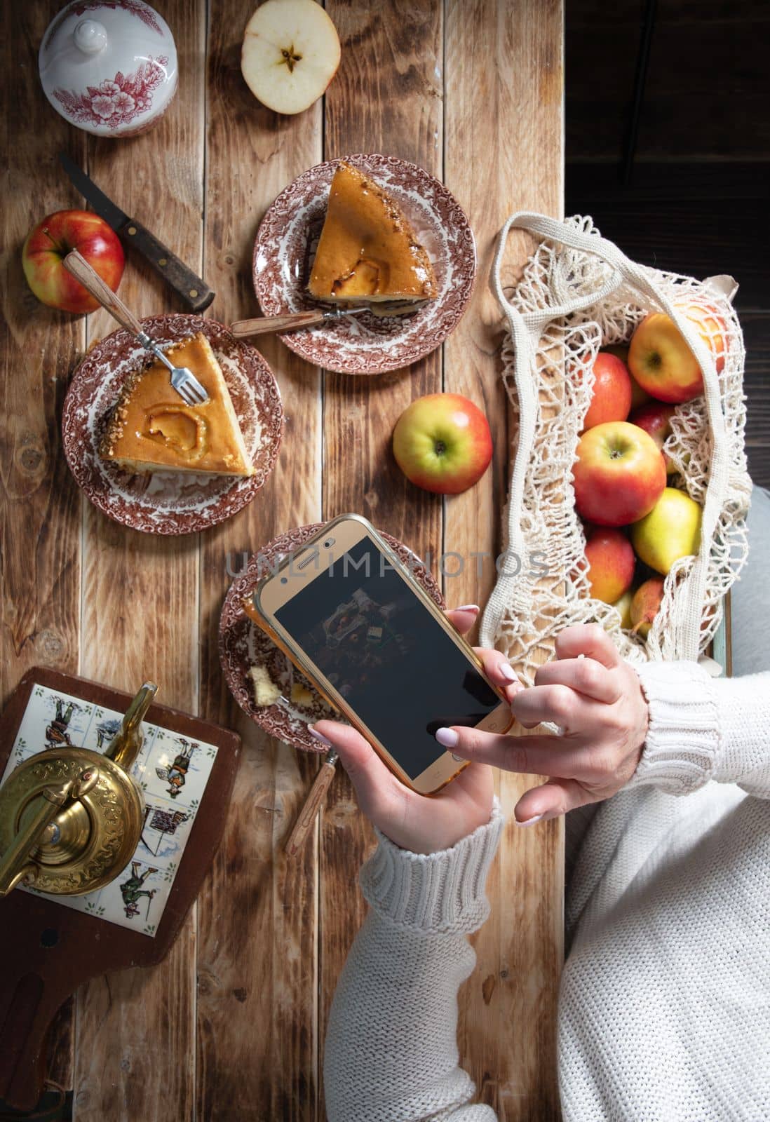 blogger girl photographing Thanksgiving apple pie table setting with mobile phone. High quality photo