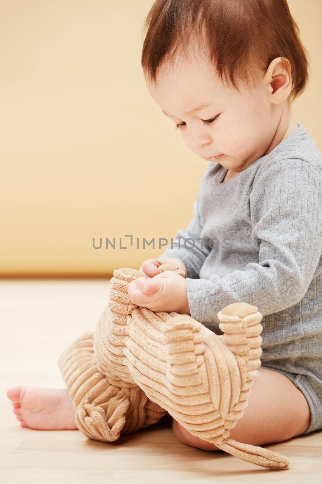 Curious about his new toy...an adorable baby boy playing with a stuffed animal