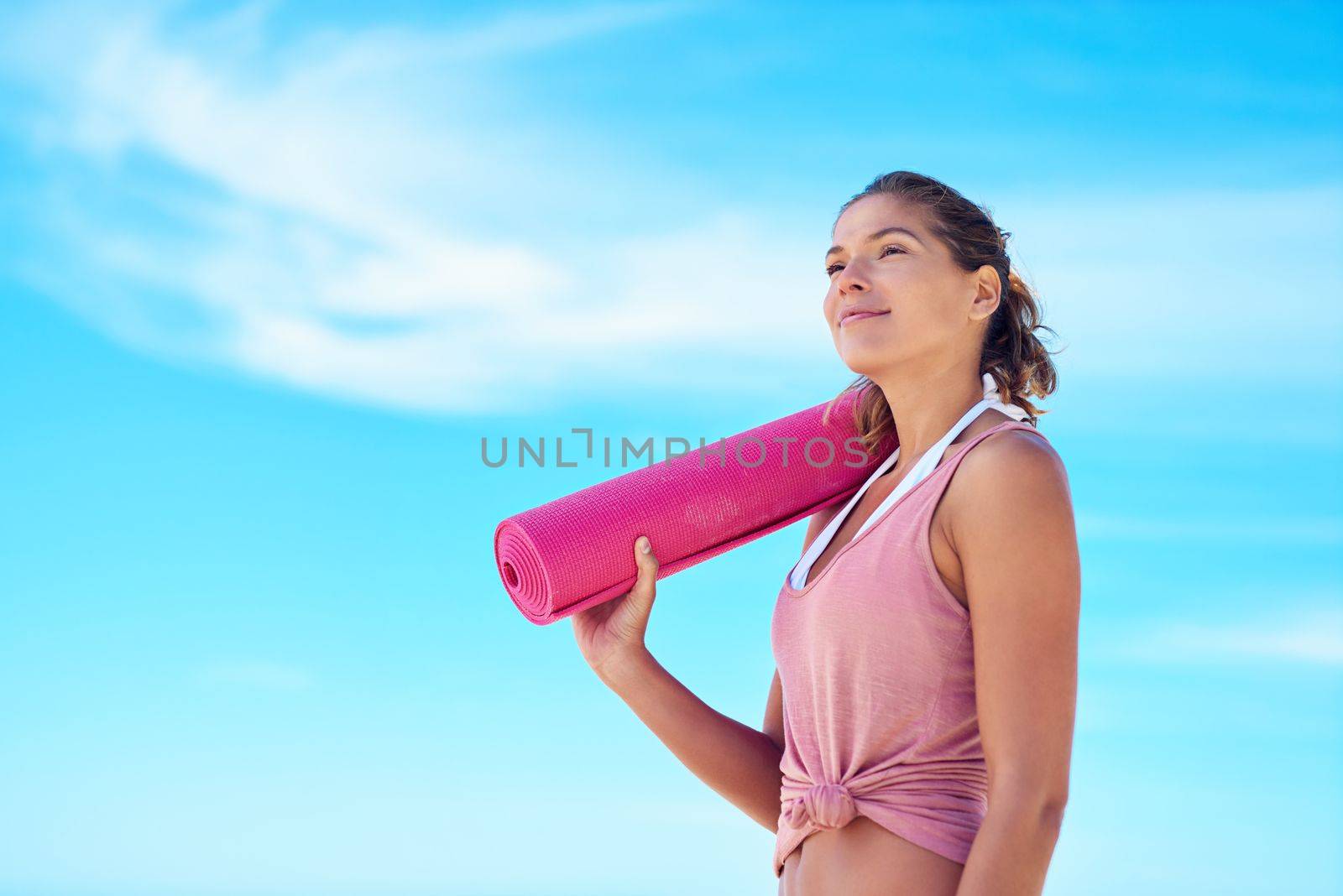 Yoga agrees with nature. a young woman holding a yoga mat while standing outside. by YuriArcurs