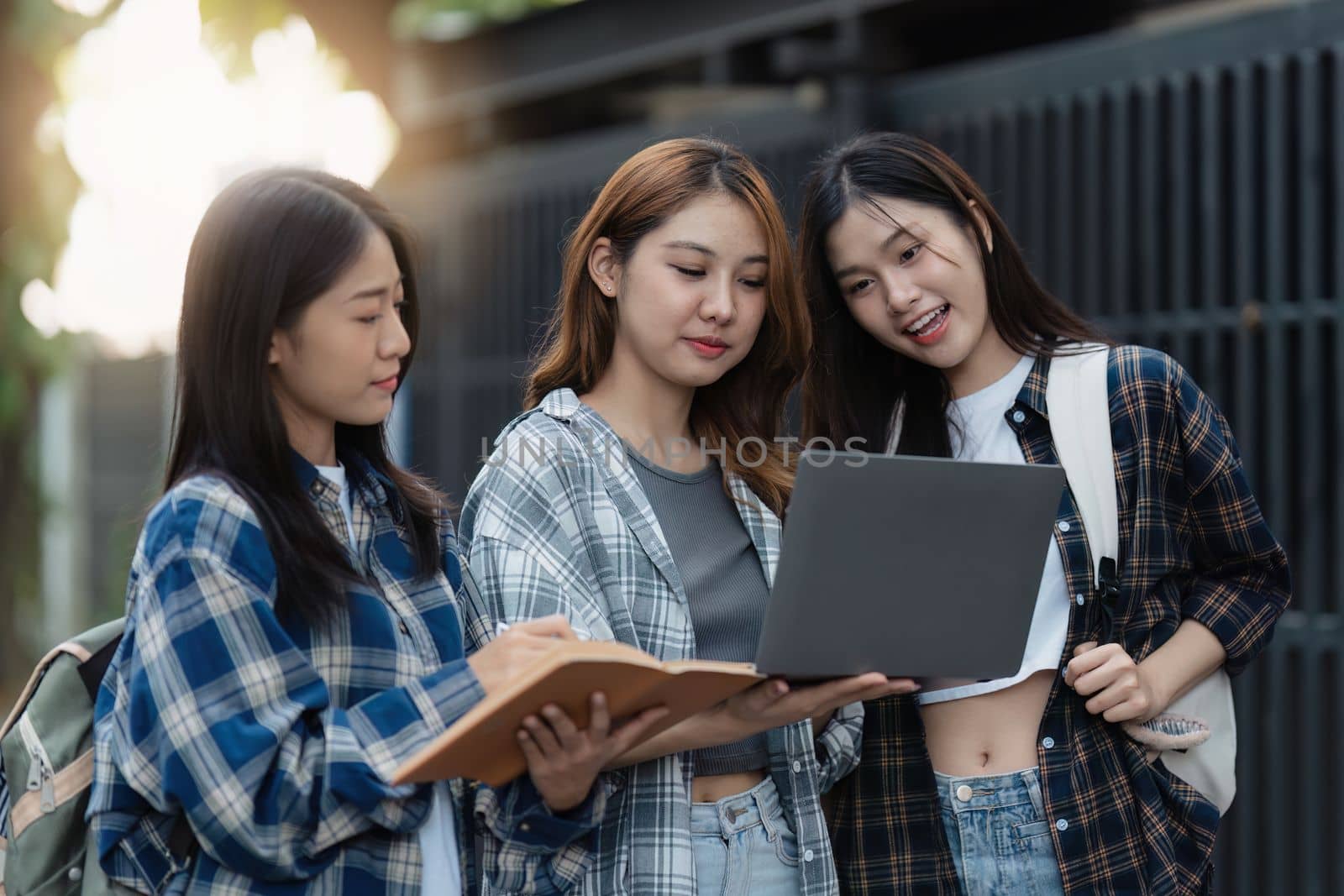 Beautiful young Asian woman college student with friends at outdoors. College student working on the college campus.