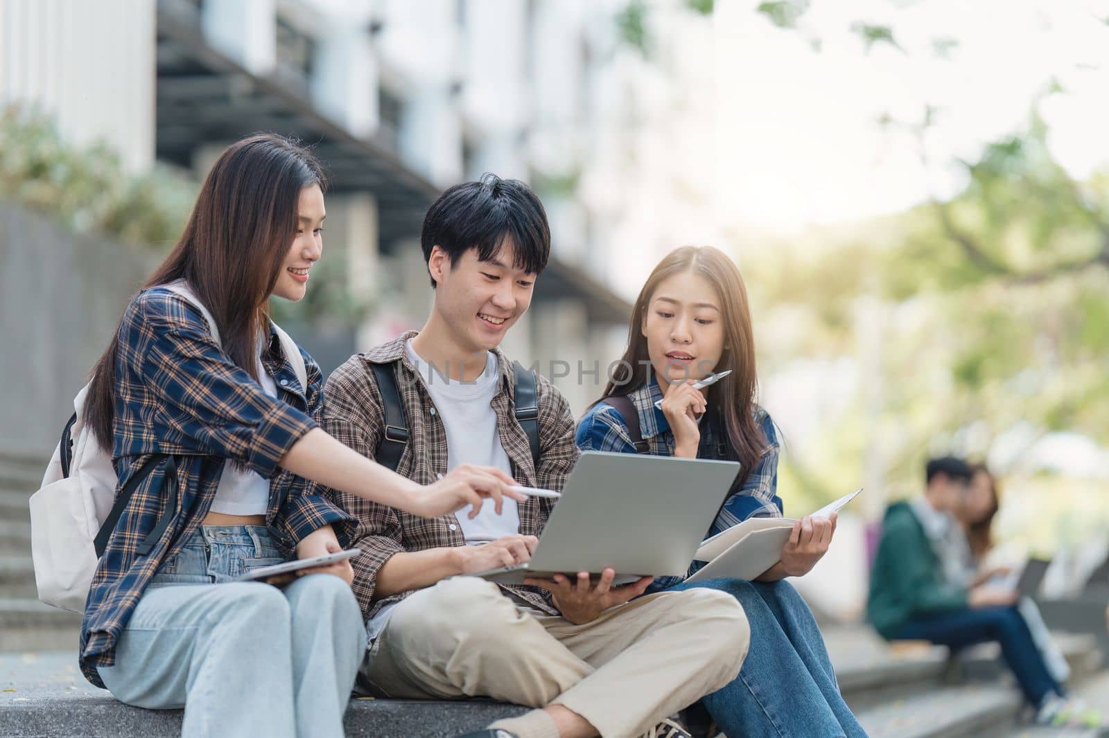 Beautiful young Asian woman college student with friends at outdoors. College student working on the college campus.