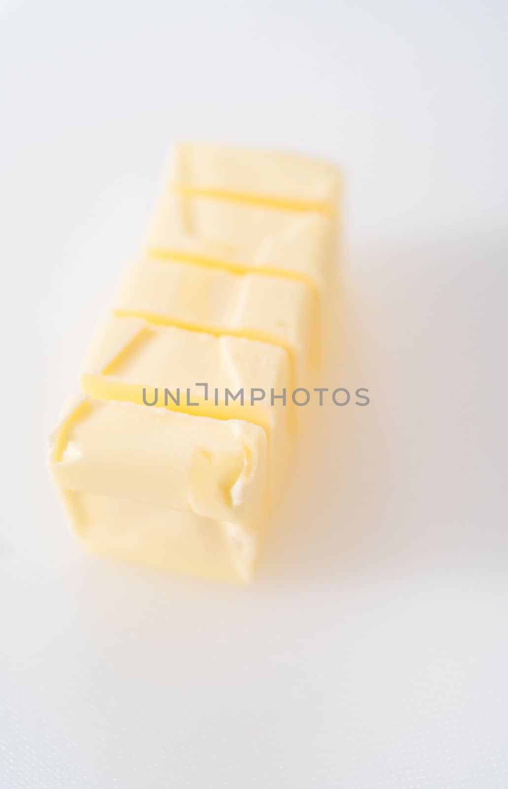 Slicing sticks of unsalted butter on a white cutting board.