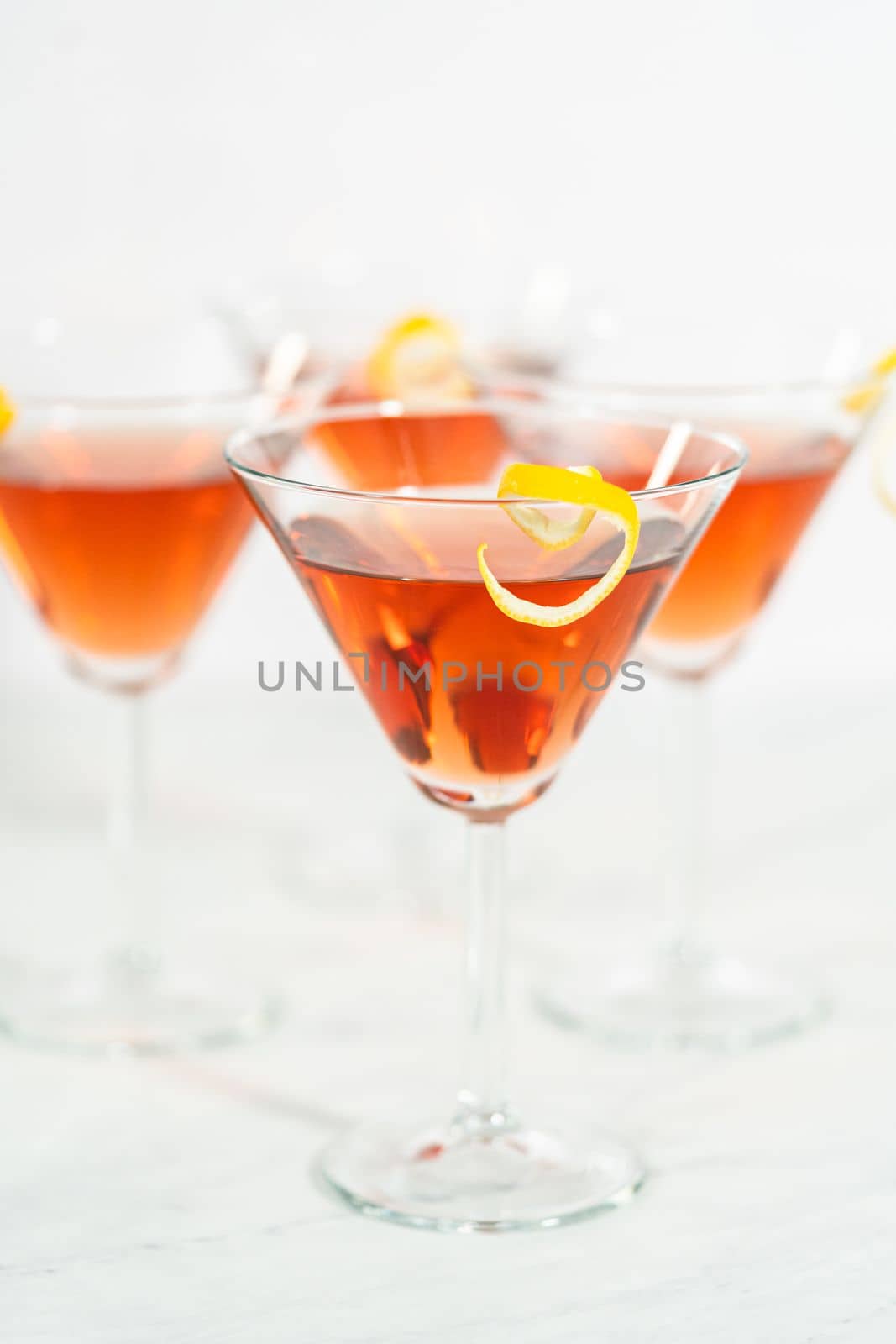 Cosmopolitan cocktail in a martini glass and decorated with a lemon swirl.