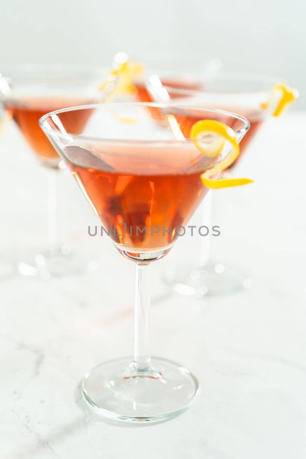 Cosmopolitan cocktail in a martini glass and decorated with a lemon swirl.