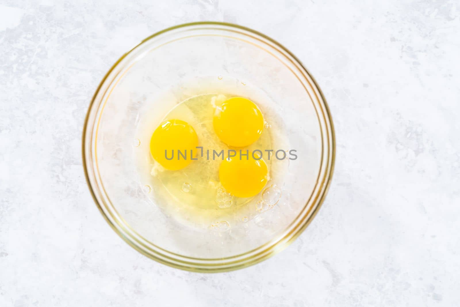 Mixing ingredients in a glass mixing bowl to bake funfettti bundt cake.