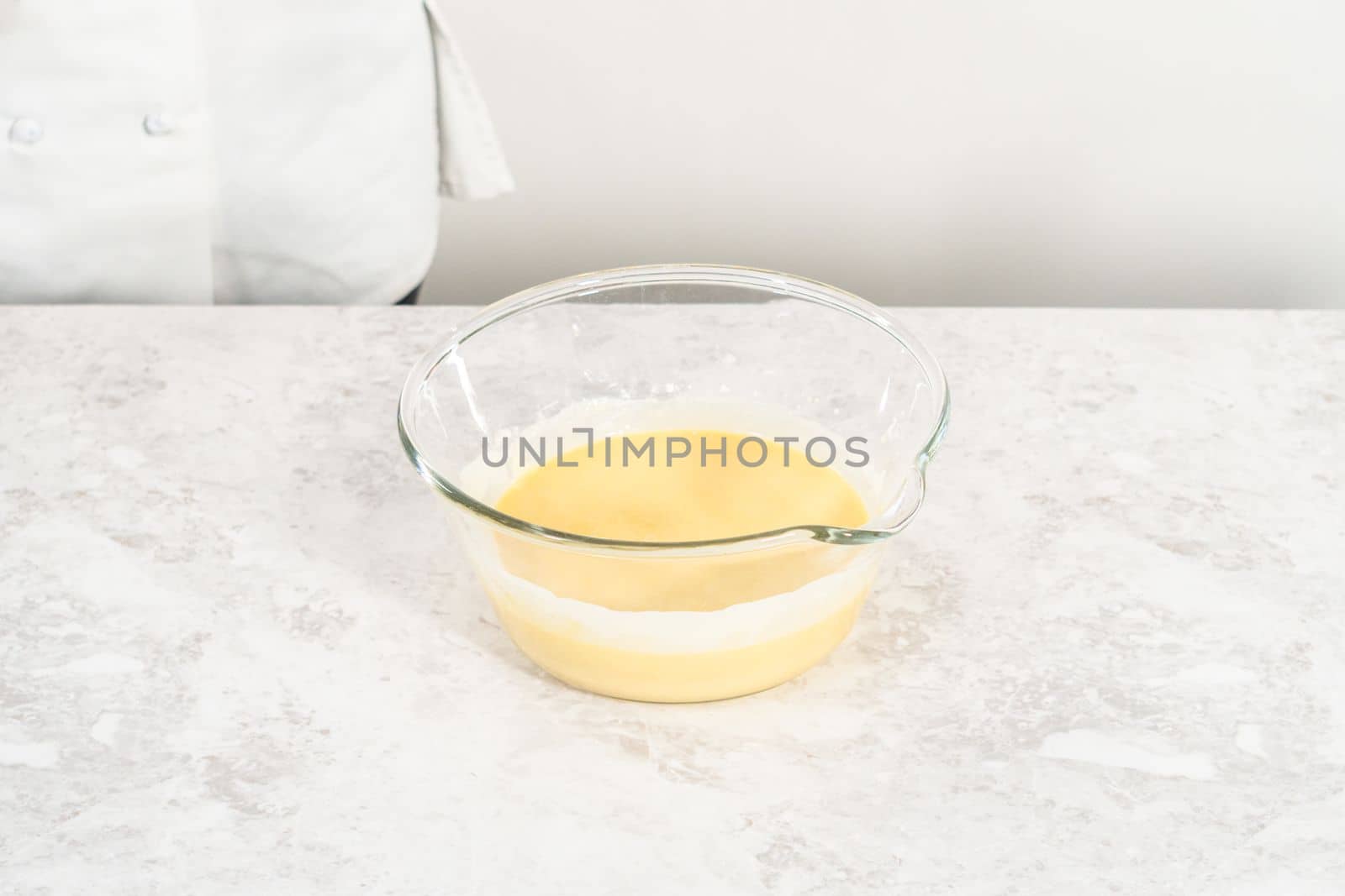 Mixing ingredients in a glass mixing bowl to bake funfettti bundt cake.