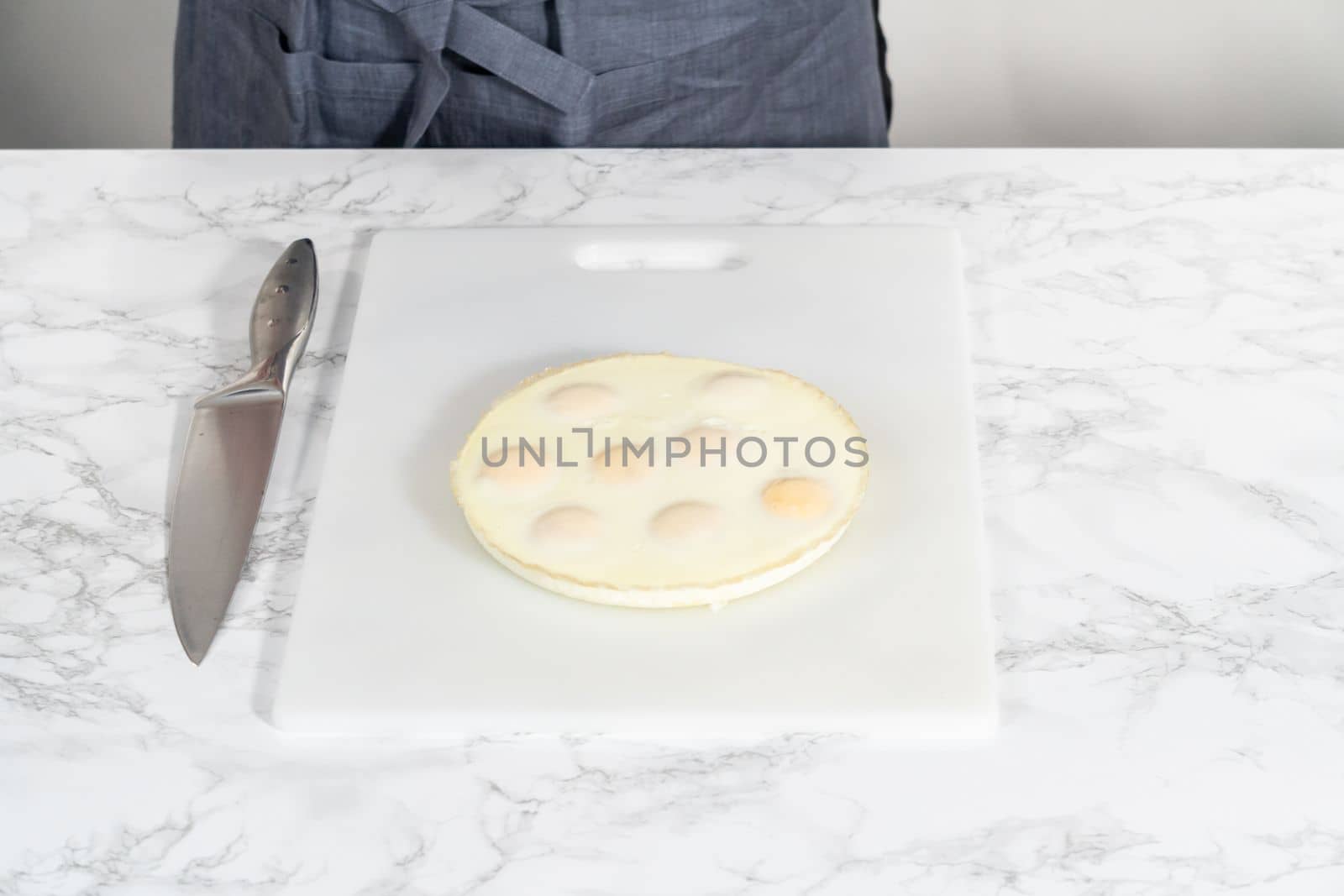 Cutting hard-boiled eggs in a shape of a loaf on a white cutting board.