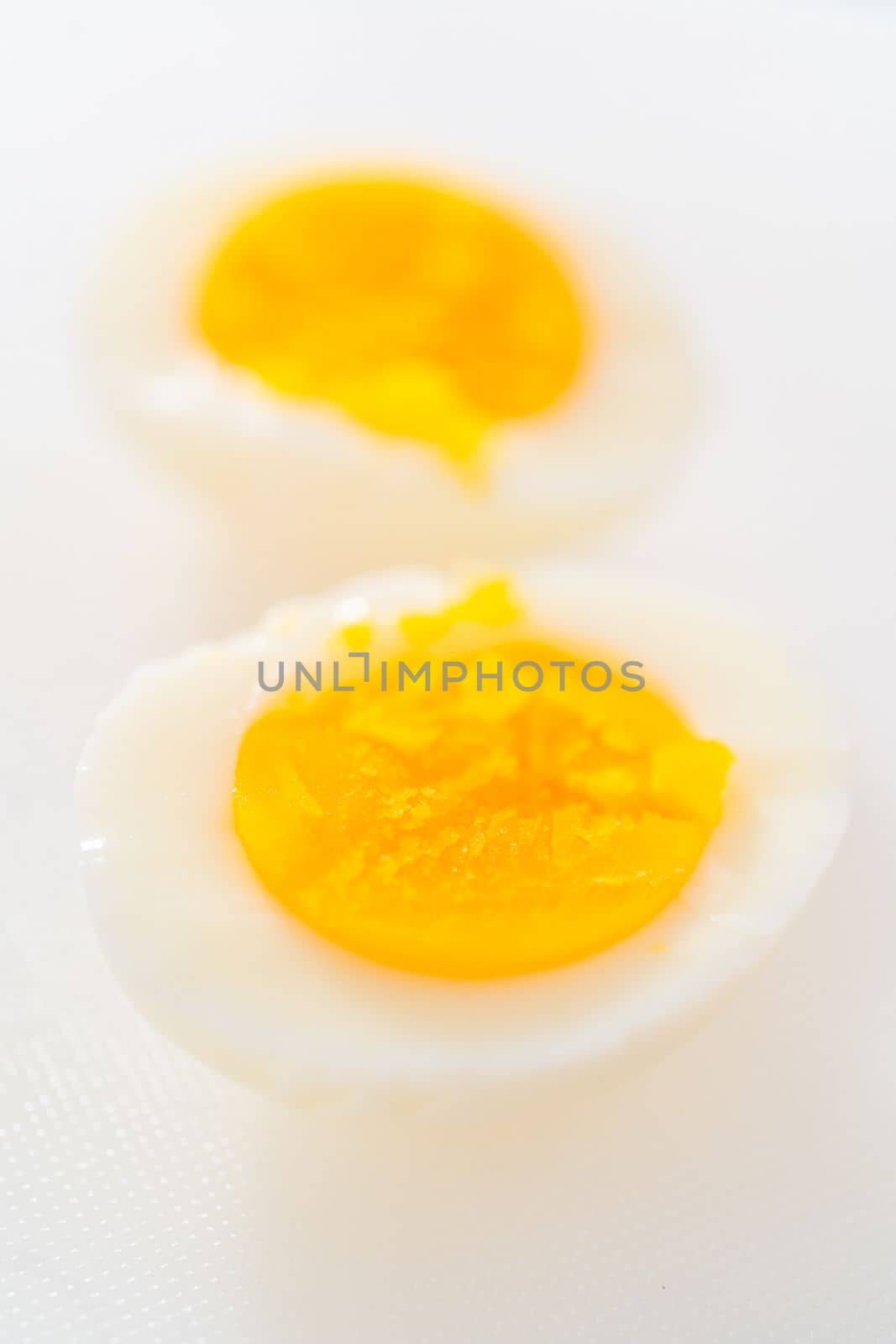 Slicing hard-boiled eggs on a white cutting board.