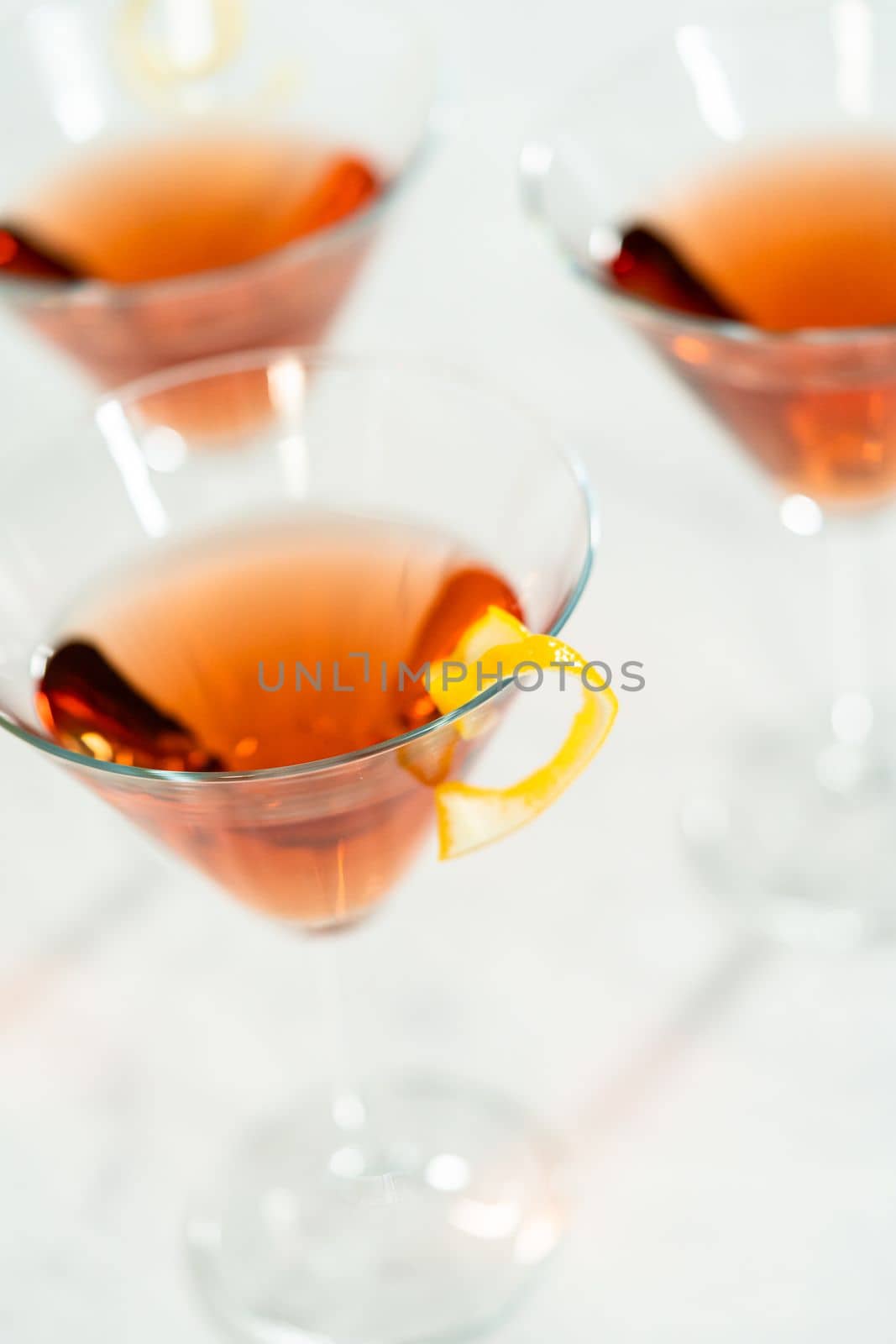 Cosmopolitan cocktail in a martini glass and decorated with a lemon swirl.